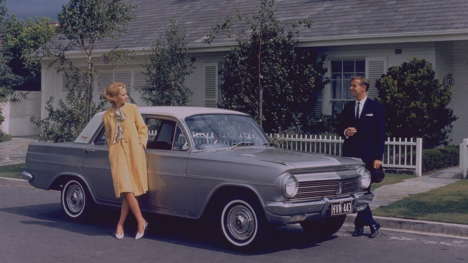 A Man and Woman Standing by a 1950s Holden